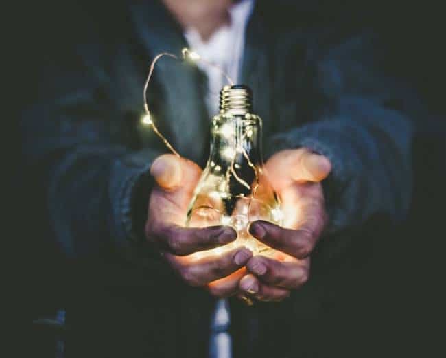 Hands holding a lit lightbulb to represent an idea