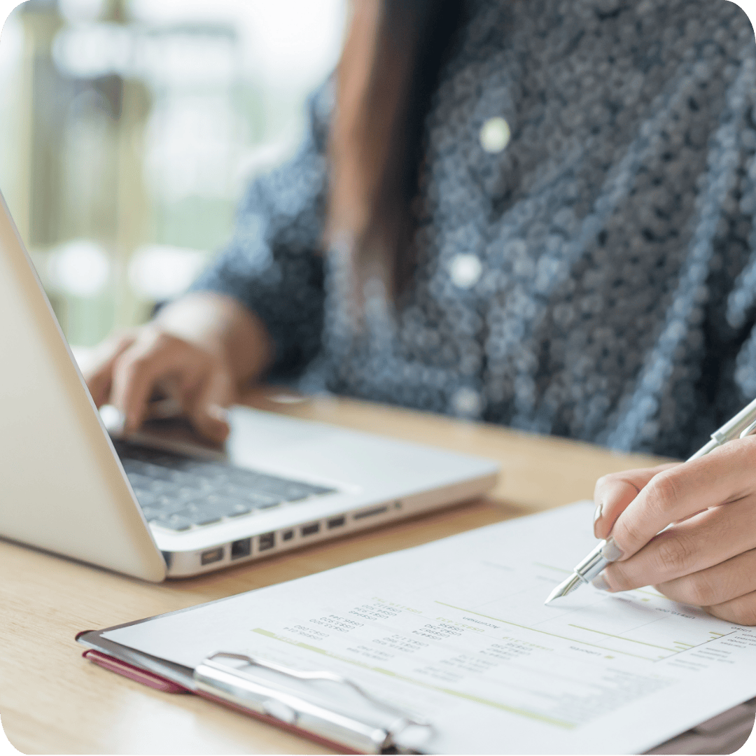 Employee at laptop writing with a pen