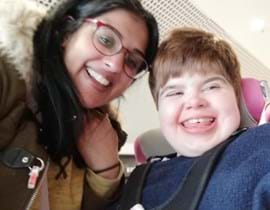Lady wearing glasses, smiling with a smiling child in her care