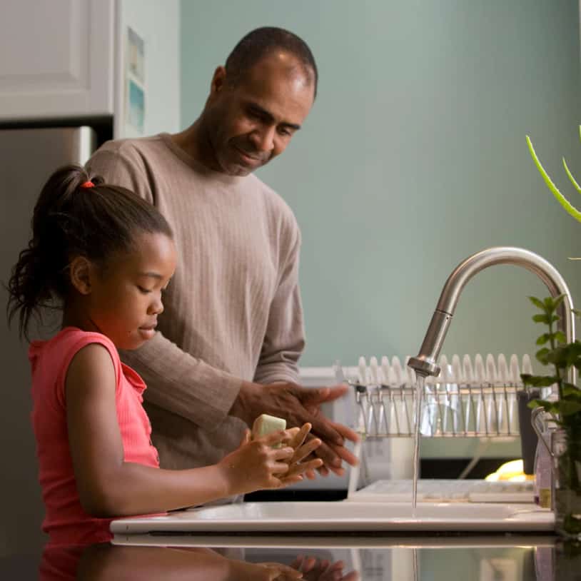 Father watching his daughter washing her hands at the sink