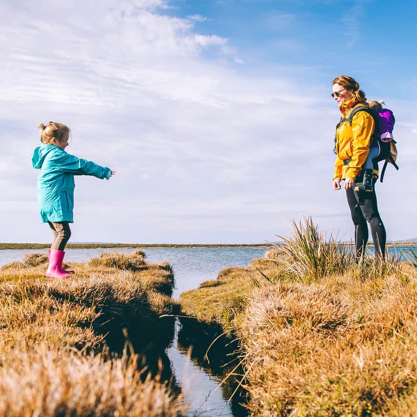 Mother and daughter on a walk, waiting to jump over water