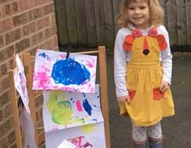 Little girl proudly displaying her paintings