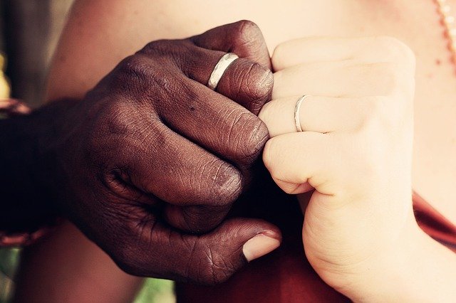 Couple touch hands wearing wedding rings